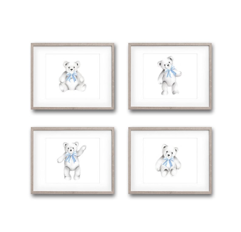 May include: Set of four framed prints featuring watercolor illustrations of white teddy bears with blue bows. Each print is in a simple gray frame.