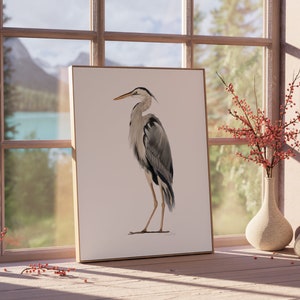 May include: A framed print of a grey heron standing on a white background. The heron is facing to the left and has a long, thin beak. The print is in a wooden frame and is hanging on a wall.
