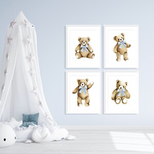 May include: Four framed prints of watercolor illustrations of teddy bears with blue bows. The bears are in different poses, including sitting, standing, and waving. The prints are on a light blue wall.