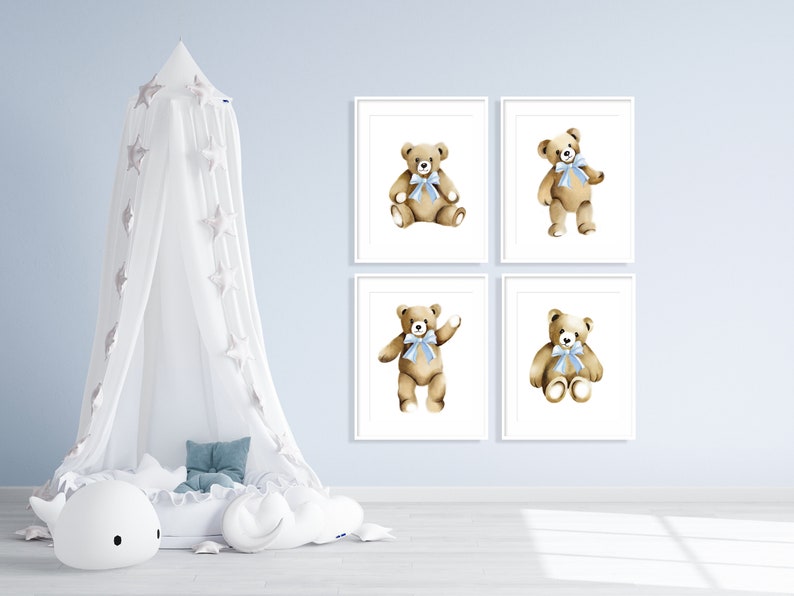 May include: Four framed prints of watercolor illustrations of teddy bears with blue bows. The bears are in different poses, including sitting, standing, and waving. The prints are on a light blue wall.