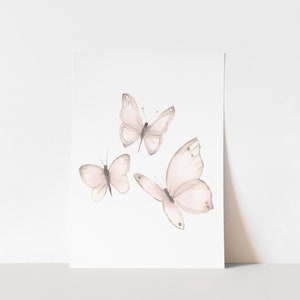 May include: Three delicate watercolor butterflies in shades of pink and gray on a white background.