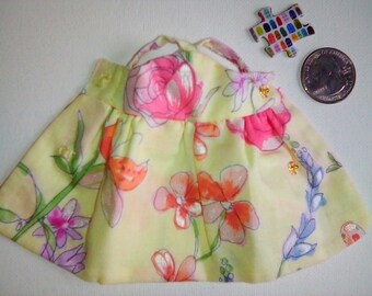May include: A yellow floral print dress with pink and orange flowers. The dress has a ruffled hem and a halter neckline.
