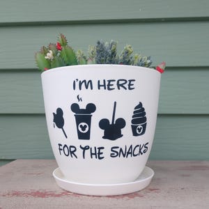 May include: White ceramic planter with a black Mickey Mouse design and the text "I'm here for the snacks".