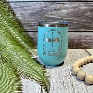 May include: A light blue stainless steel tumbler with a silver design that reads "There's nowhere in existence you could go that I wouldn't find you. Violence." The tumbler features a crescent moon and a dragon.