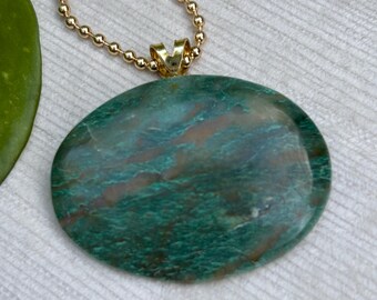May include: A green and brown oval pendant with a gold chain. The pendant has a marbled pattern.