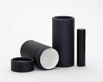 May include: Three black cardboard tubes, one with the top removed, revealing a white interior. The tubes are different sizes, with the largest tube standing upright and the smallest tube lying on its side. The tubes are made of cardboard and have a smooth, matte finish.