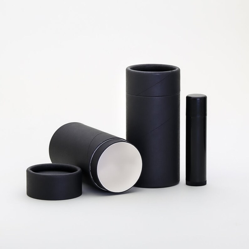 May include: Three black cardboard tubes, one with the top removed, revealing a white interior. The tubes are of different sizes, with the largest tube standing upright and the smallest tube lying on its side. The tubes are made of cardboard and have a smooth, matte finish.