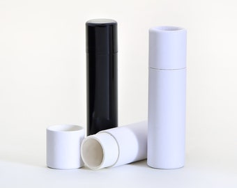 May include: A collection of cylindrical paperboard tubes in black and white. One black tube stands upright, while the others are white, with one lying on its side. The tubes have removable lids, suggesting packaging or storage.