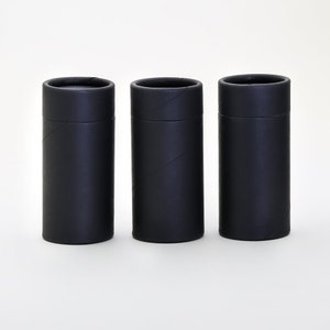 May include: Three black cardboard tubes, each with a slightly different texture, are lined up in a row on a white surface.