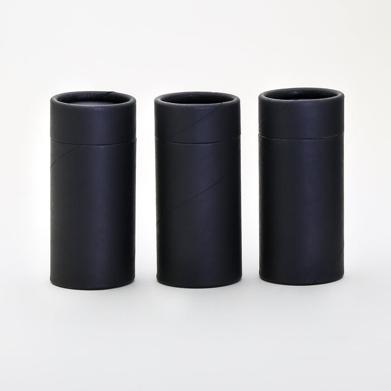 May include: Three black cardboard tubes, each with a slightly different texture, are lined up in a row on a white surface.