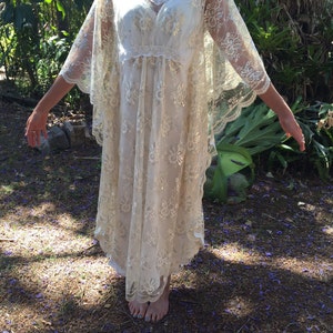 K&ouml;nnte beinhalten: Ein wei&szlig;es Maxikleid aus Spitze mit V-Ausschnitt und langen, flie&szlig;enden &Auml;rmeln. Das Kleid hat ein zartes Blumenmuster und eine lockere, flie&szlig;ende Passform.