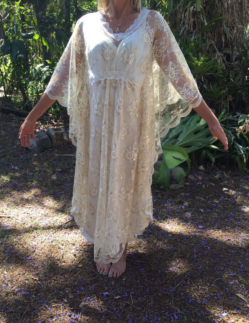 K&ouml;nnte beinhalten: Ein wei&szlig;es Maxikleid aus Spitze mit V-Ausschnitt und langen, flie&szlig;enden &Auml;rmeln. Das Kleid hat ein zartes Blumenmuster und eine lockere, flie&szlig;ende Passform.