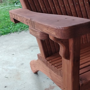 Peut inclure: Une chaise Adirondack en bois avec une teinte brun rouge&acirc;tre. La chaise a un accoudoir incurv&eacute; et un dossier et un si&egrave;ge &agrave; lattes.
