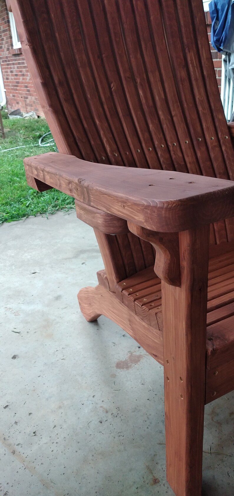 Peut inclure: Une chaise Adirondack en bois avec une teinte brun rouge&acirc;tre. La chaise a un accoudoir incurv&eacute; et un dossier et un si&egrave;ge &agrave; lattes.