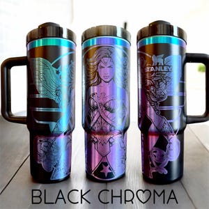 May include: Three black stainless steel travel mugs with iridescent accents and black handles. Each mug features a different Wonder Woman design. The text "BLACK CHROMA" is at the bottom of the image.