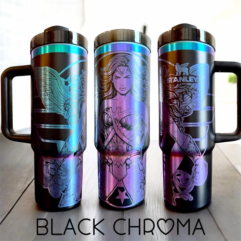 May include: Three black stainless steel travel mugs with iridescent accents and black handles. Each mug features a different Wonder Woman design. The text "BLACK CHROMA" is at the bottom of the image.