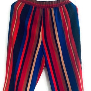 May include: Multi-coloured striped trousers with vertical stripes in red, blue, brown, and tan. The trousers have an elasticated waistband and a wide-leg design. The word "Vintage" is in the bottom left corner.
