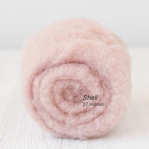 Könnte beinhalten: Nahaufnahme einer hellrosa Wollfaserrolle. Das Etikett lautet "Shell 27 Mikron".