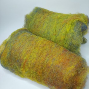 Könnte beinhalten: Zwei Rollen bunte Wollvlies in den Farben Gelb, Grün, Blau und Braun. Das Vlies ist weich und flauschig, perfekt zum Spinnen oder Filzen.