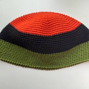 Puede incluir: Un gorro de punto de lana con rayas rojas, negras y verdes.