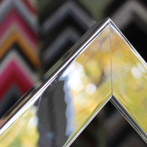 May include: Close-up of a silver picture frame with a bevelled edge. The frame is reflecting the light from the surrounding environment.