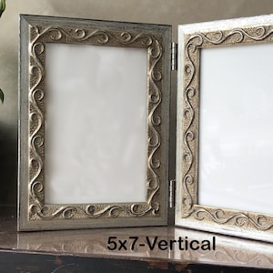 May include: A silver-toned, ornate picture frame with two vertical openings. The frame is designed to hold two 5x7 inch photos.