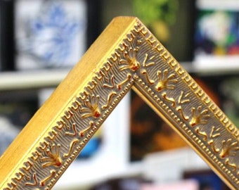 May include: A gold picture frame with a decorative silver and gold design. The frame has a beveled edge and a raised design.