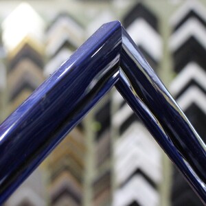 May include: A close-up of a dark blue picture frame with a glossy finish. The frame is made of wood and has a simple, elegant design.
