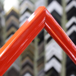 May include: A bright red picture frame with a glossy finish. The frame is made of wood and has a simple, modern design.