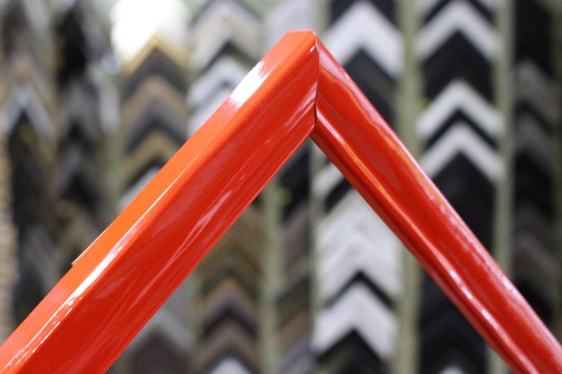 May include: A bright red picture frame with a glossy finish. The frame is made of wood and has a simple, modern design.