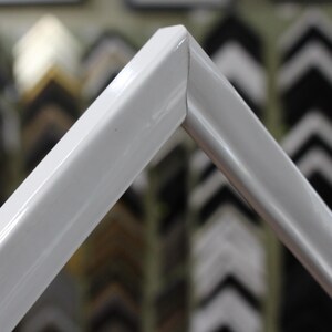 May include: Close-up of a white picture frame with a smooth, glossy finish. The frame is made of a sturdy material and has a simple, modern design.