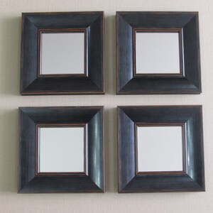 May include: Four square black framed mirrors with a dark brown inner border. The mirrors are arranged in a two by two grid.