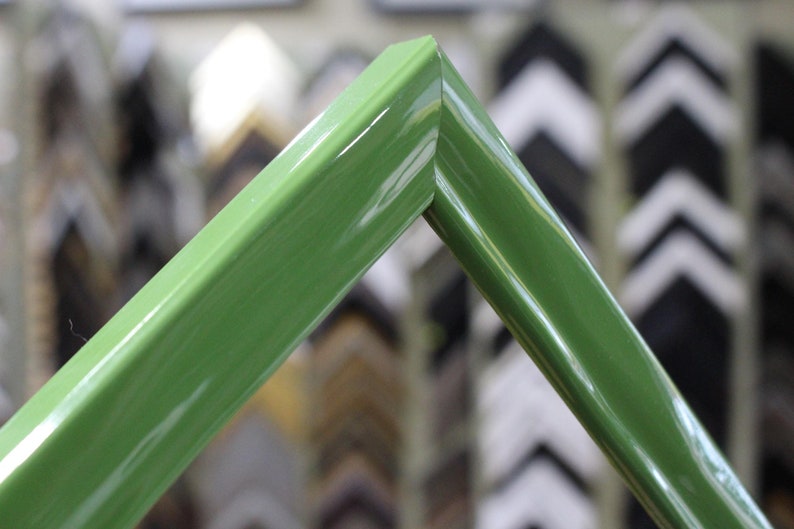 May include: Close-up of a green picture frame with a glossy finish. The frame is made of wood and has a simple, modern design.