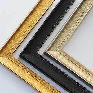 Puede incluir: Tres marcos de fotos de diferentes tamaños y colores. El marco más grande es dorado con un borde decorativo. El marco del medio es negro con un borde simple. El marco más pequeño es plateado con un borde decorativo.