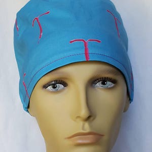 Peut inclure: Un bonnet de chirurgien bleu clair avec un motif d'utérus en rose.