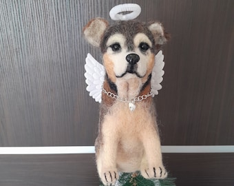 May include: A handcrafted felt dog figurine with angel wings and a halo. The dog has brown and tan fur, a silver chain collar, and is perched atop a small Christmas tree. The wings and halo are white.
