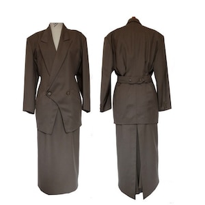 May include: A brown skirt suit with a long skirt and a double-breasted blazer. The blazer has a single button closure and a belt.