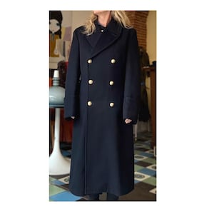 Peut inclure: Un long manteau bleu marine à double boutonnage avec des boutons dorés. Le manteau a un design classique avec un col cranté et une coupe ajustée. Les manches ont un détail de poignet.