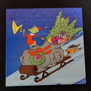May include: A green Grinch character wearing a red Santa suit is pulling a large sack filled with presents and a Christmas tree on a wooden sled. The Grinch is blowing a yellow horn and a brown dog is running behind the sled.