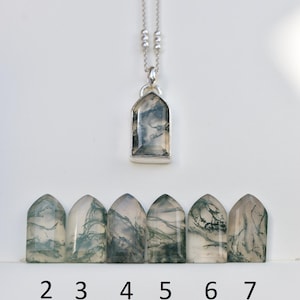 May include: A silver necklace with a pointed arch pendant containing a moss agate stone with green inclusions. Below are six loose, matching moss agate stones in the same pointed arch shape, labeled with the numbers 2, 3, 4, 5, 6, and 7.