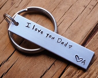 May include: Silver keyring with a rectangular tag that reads "I love you Dad" with a heart symbol. The tag has a small heart with the letter "A" inside.