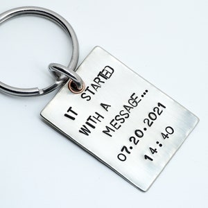 May include: Silver keyring with a rectangular tag that reads "It started with a message... 07.20.2021 14:40".