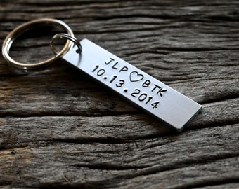 Op de afbeelding: Zilveren sleutelhanger met een rechthoekig label gegraveerd met "JLP ♥ BTK 10.13.2014".
