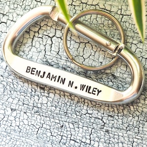 May include: Silver metal carabiner keychain with a ring and the engraved text "BENJAMIN N. WILEY".