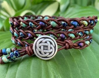 May include: A brown leather wrap bracelet with blue and green glass beads and a silver Celtic knot button closure.