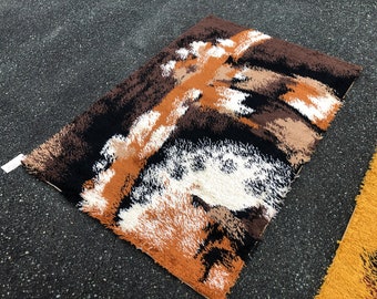 May include: Rectangular rug with a textured, abstract design in shades of brown, black, tan, and white. The rug has a shaggy appearance and a soft texture. The rug is likely made of a synthetic material.