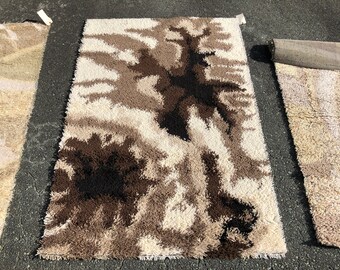 May include: A shag rug with an abstract pattern in brown, black and white. The rug has a long, shaggy pile and is made from synthetic fibres.