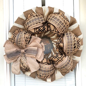 May include: A brown and white burlap wreath with a large brown bow and black and white patterned ribbon accents.