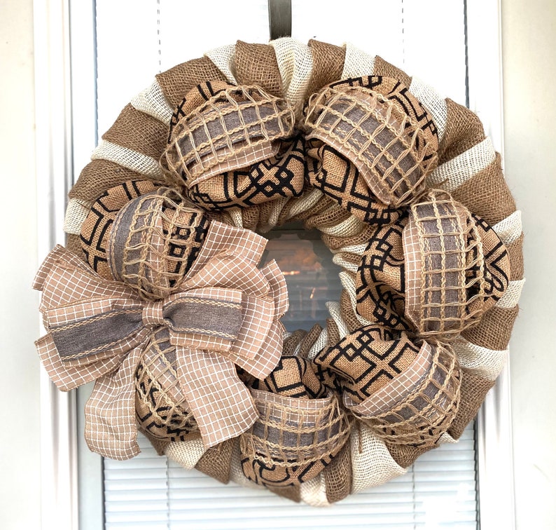 May include: A brown and white burlap wreath with a large brown bow and black and white patterned ribbon accents.