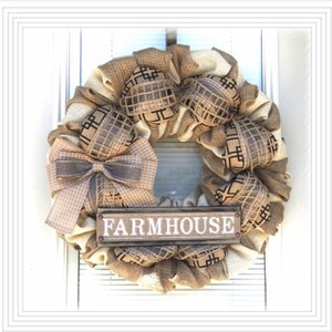 May include: A burlap wreath with a brown and black checkered ribbon bow and a wooden sign that says "FARMHOUSE".